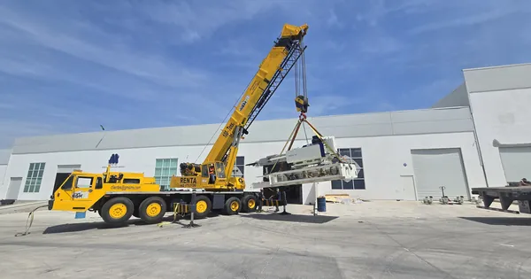 Grúa introduciendo maquinaria a una nave industrial