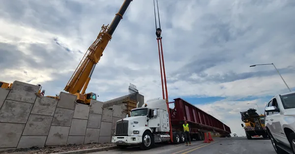 Grúa izando una trabe bajo un cielo nublado