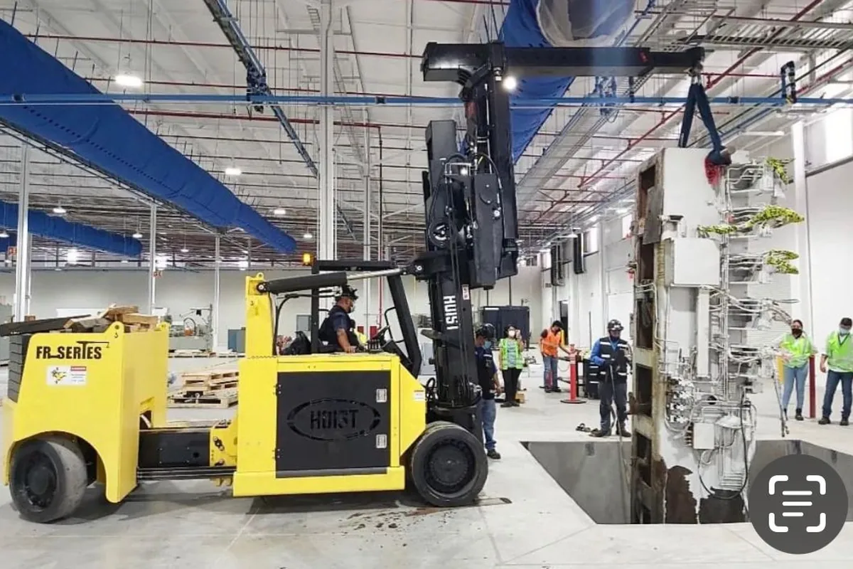 Versa-Lift bajando maquinaria a un foso dentro de una planta