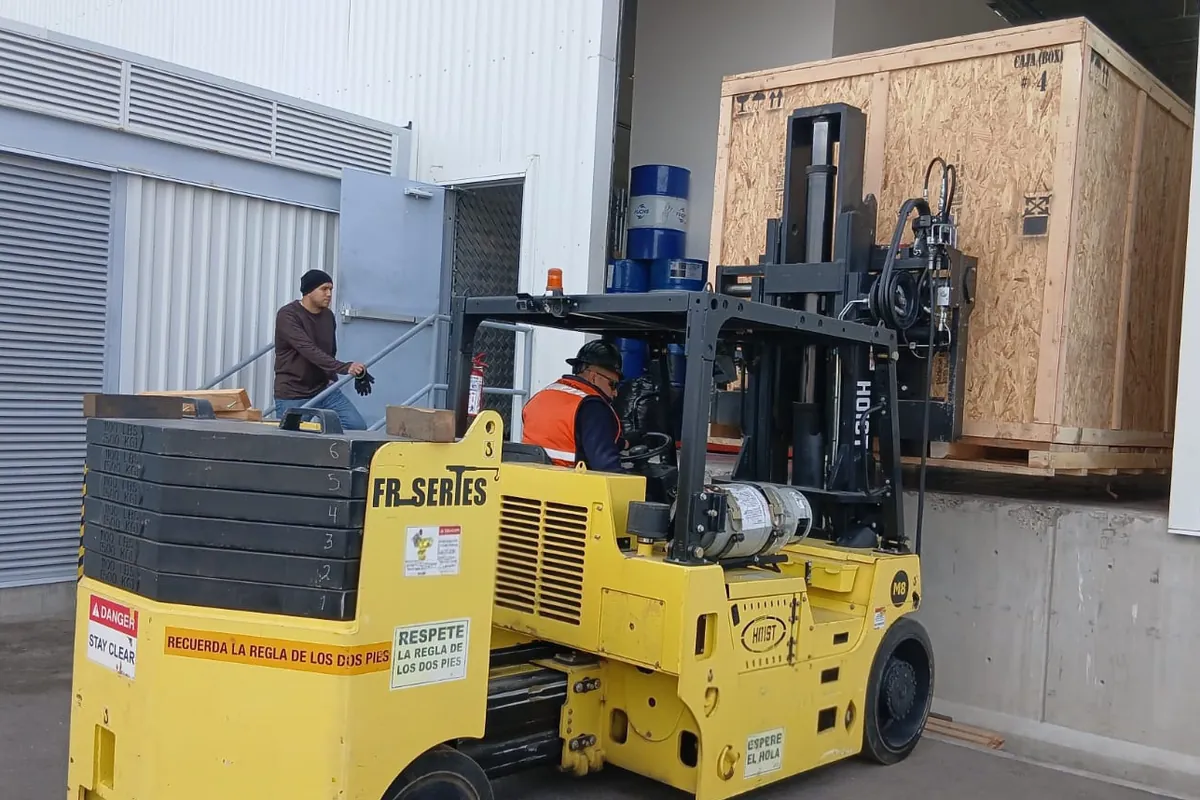 Montacargas de alta capacidad descargando una caja de madera en el andén