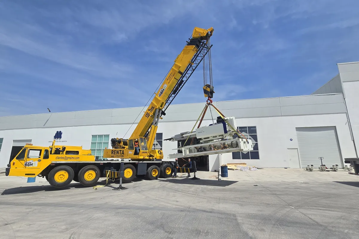 Grúa Grove de 100 toneladas de GMSI introduciendo maquinaria a una nave industrial